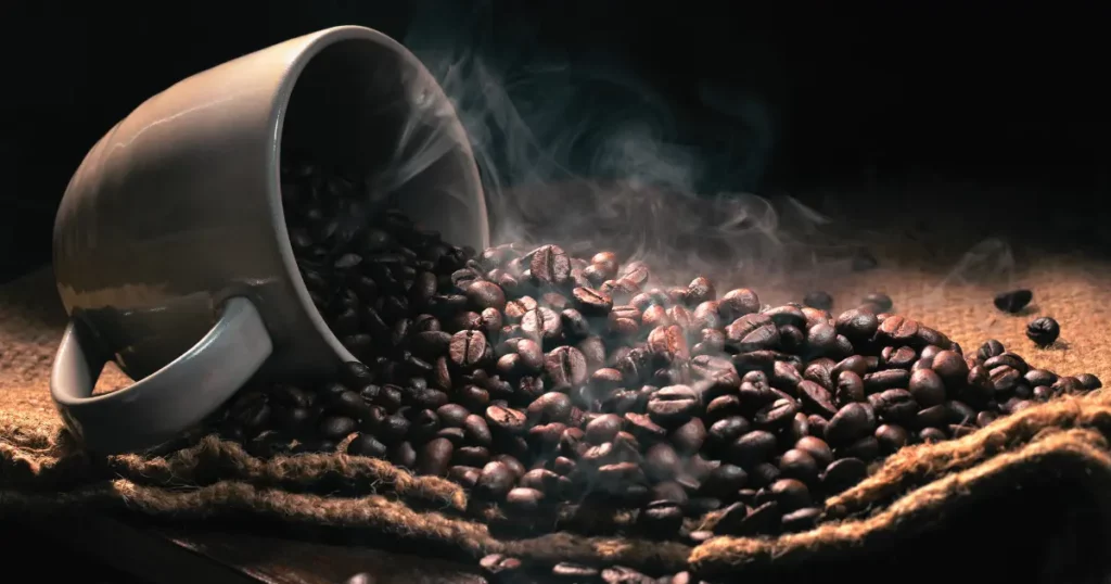 coffee beans and a cup of coffee on a wooden table with smoke | hustle coffee