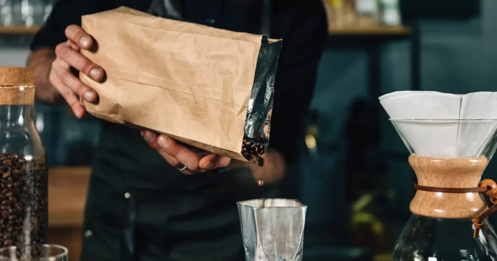 a barista is pouring coffee into a paper bag | hustle coffee