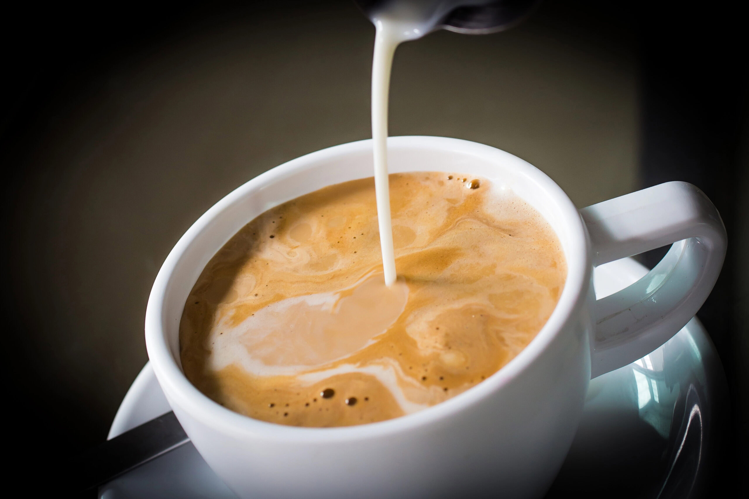 pouring cream into coffee | Hustle Coffee