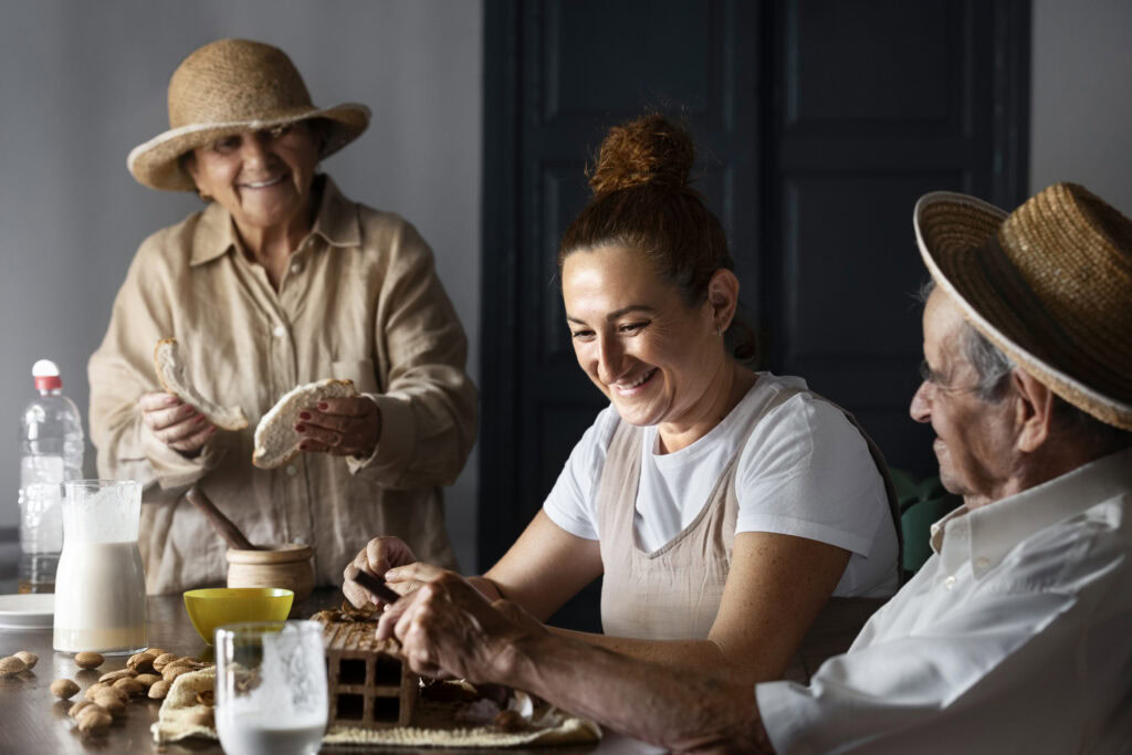 Three people in straw hats enjoy bread and milk together at a table, smiling and sharing food in a cozy room. | Hustle Coffee