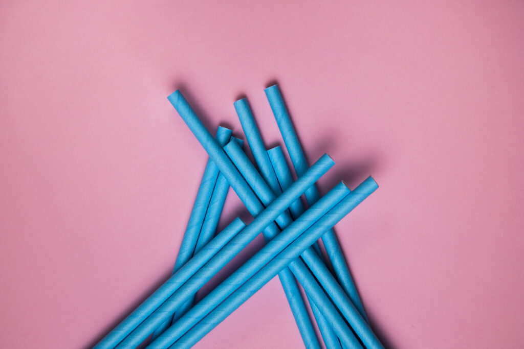 Several blue straws arranged on a pink background. | Hustle Coffee